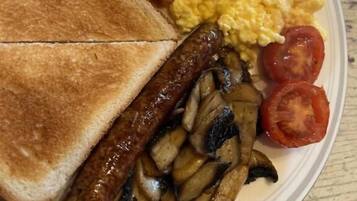 Un plato con tostadas, frijoles, huevos revueltos, salchicha, champiñones y tomates.