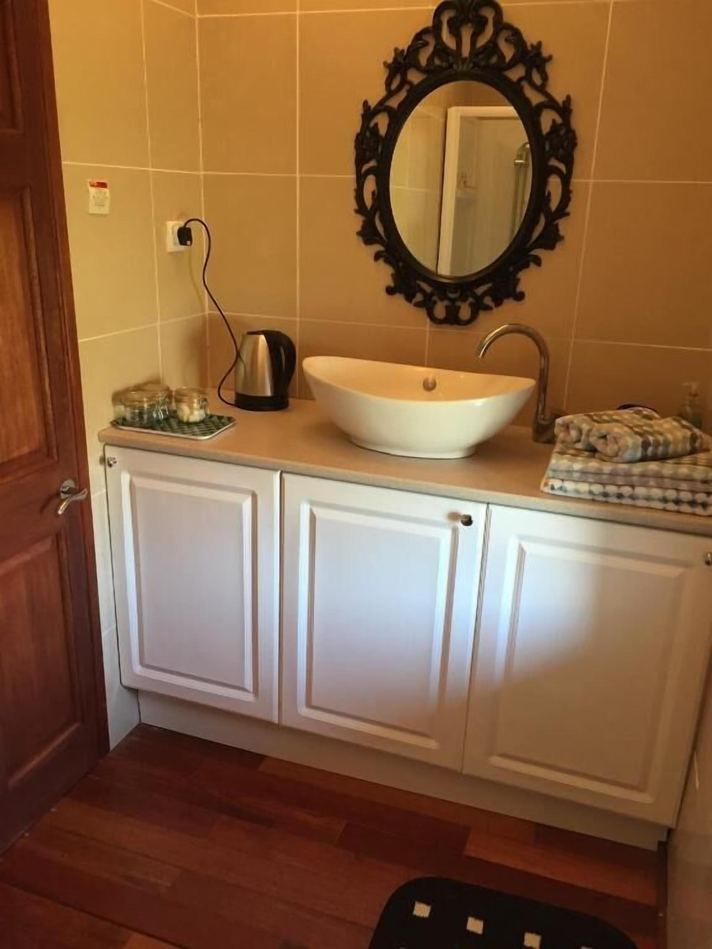 A bathroom with a white sink, a mirror, and cabinets.