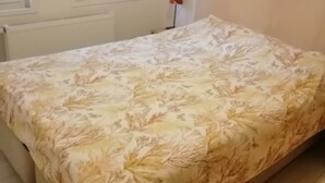 Un dormitorio con cama, ventana, radiador y un cuadro colgado en la pared.