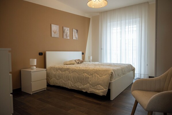 Une chambre à coucher avec un lit, des tables de chevet, une chaise et des œuvres d’art accrochées au mur.