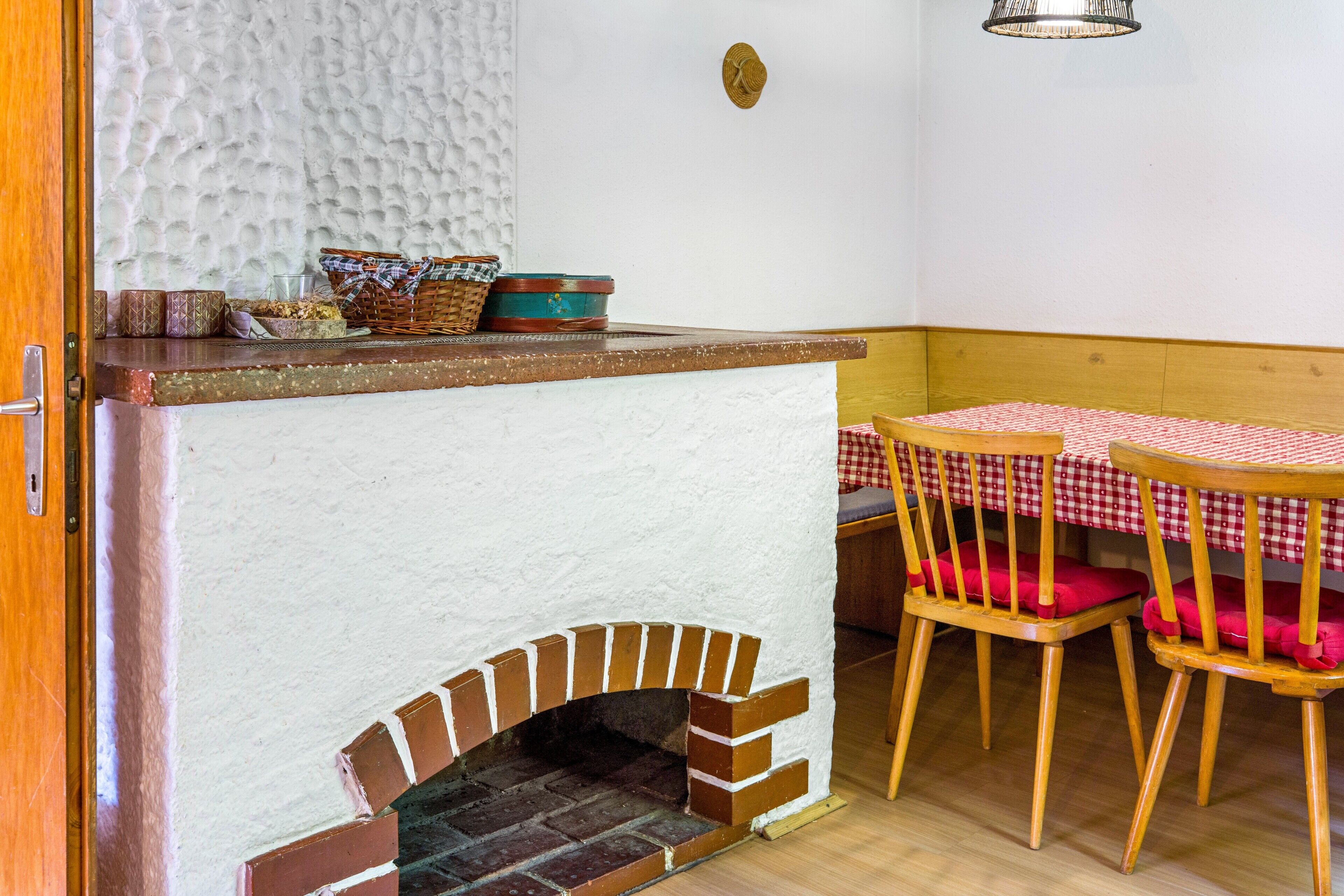 Una habitación acogedora con chimenea, un banco de madera y una mesa con mantel a cuadros.