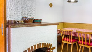 A cozy room with a fireplace, a wooden bench, and a table with a checkered tablecloth. - Spacious Holiday Home in Schetteregg – Nature, Tranquility, and Panoramic Views for the Whole Family (Egg)