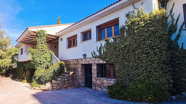 A two-story house with a stone facade, a tiled roof, and a paved driveway. - Casa Las Picoteras (La Estación)