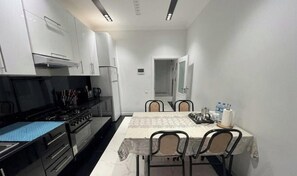 Una cocina funcional con armarios blancos, estufa y mesa de comedor con sillas.