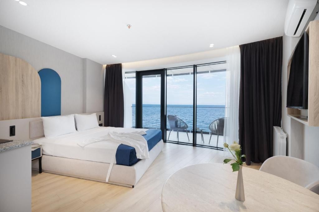 Een moderne hotelkamer met een groot bed, een zithoek en uitzicht op zee.