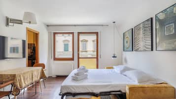 Ein Hotelzimmer mit Bett, Tisch mit Tischdecke, Stuhl, Sofa und Fernseher.
