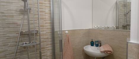 A bathroom with a glass shower enclosure, a sink with a mirror, and a toilet.