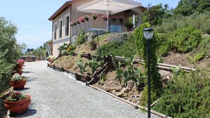 A house with a covered porch, potted plants, and a gravel path. - Apartment 'A Fosdinovo' with Mountain View, Wi-Fi and Air Conditioning (Fosdinovo)