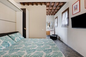 A bedroom with a bed, a wardrobe, a television, and a bathroom visible in the background. - Apartment 'Incantevole - Fosdinovo' with Mountain View, Wi-Fi and Air Conditioning (Fosdinovo)
