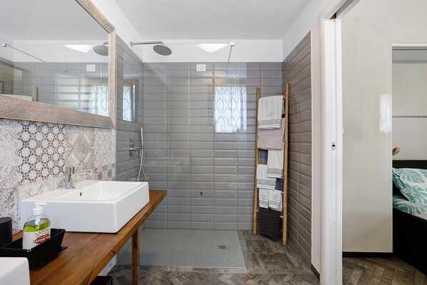 Un bagno moderno con uno specchio grande, un lavandino e una zona doccia.