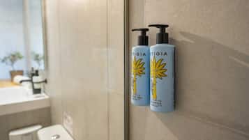 Zwei Flaschen 'ARTIGIA'-Haarpflegeprodukte an einer Badezimmerwand.