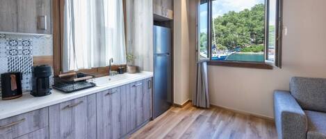 A modern kitchen with wooden cabinets, a built-in refrigerator, and a window with a view of a lake.