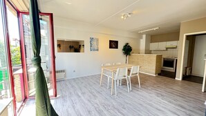 Eine moderne Wohnung mit Essbereich, Küche und einem Balkon mit Vorhängen.