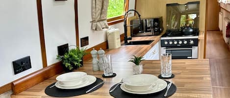 A compact kitchen with a dining area, a stove, and a window with curtains.