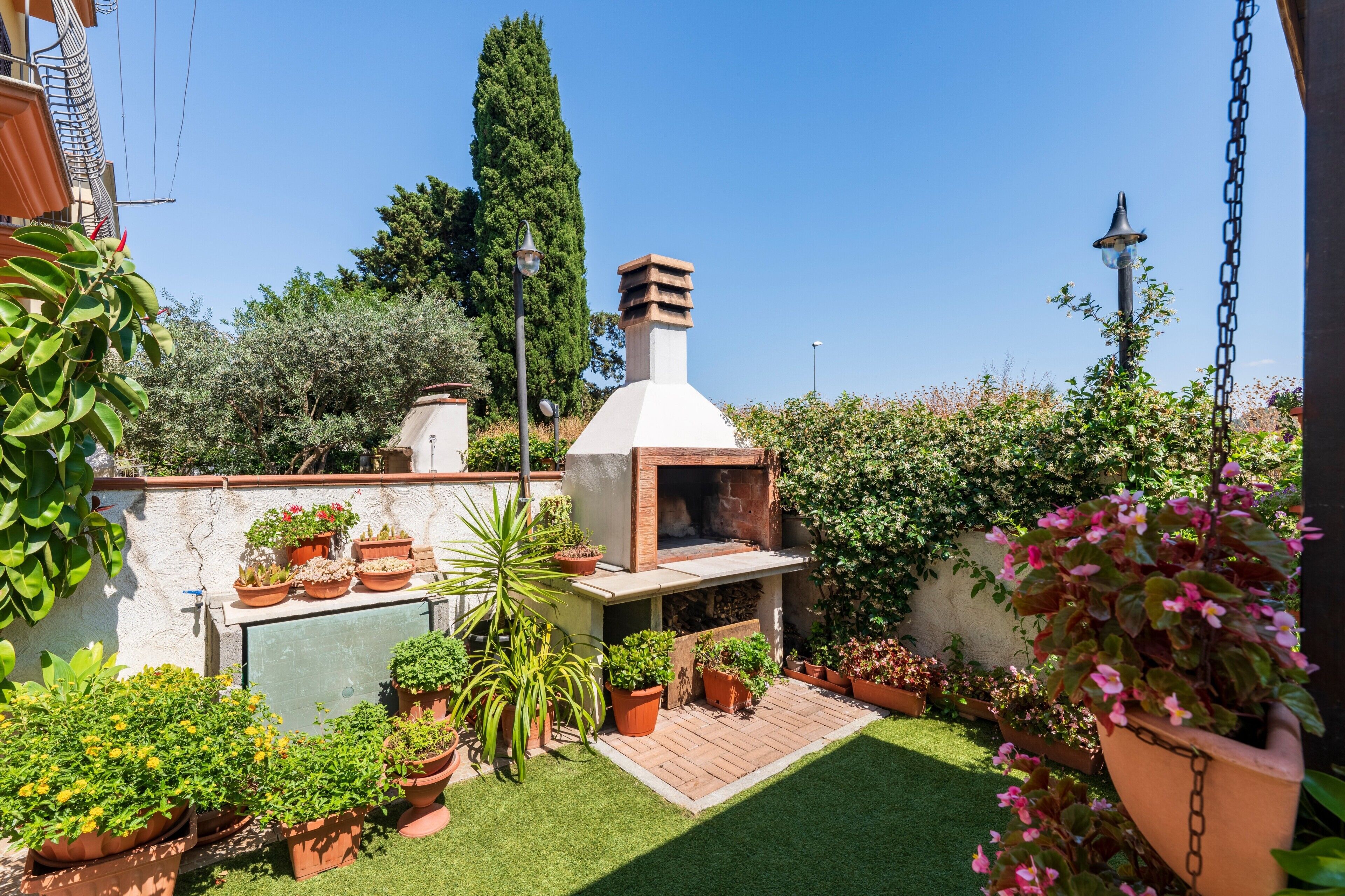 A patio with a barbecue grill, potted plants, and a small garden area.