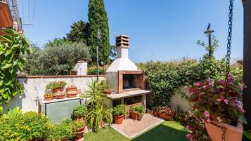 A patio with a barbecue grill, potted plants, and a small garden area.