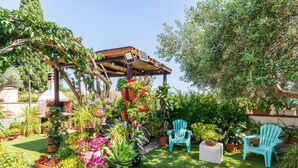 Un jardin agrémenté de plantes en pot, d’une pergola et de deux chaises bleues.