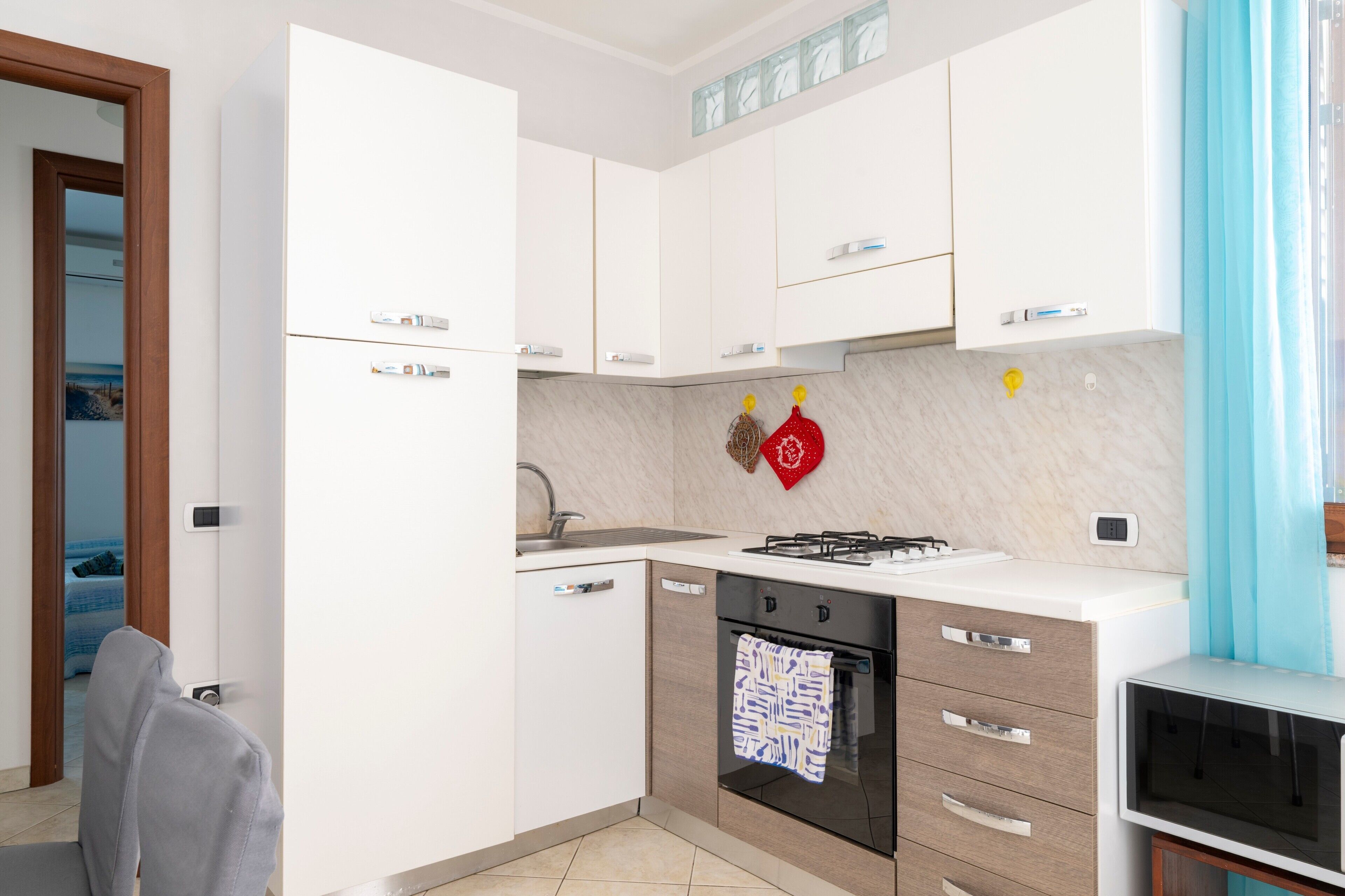 A modern kitchen with white cabinets, a built-in oven, and a microwave.