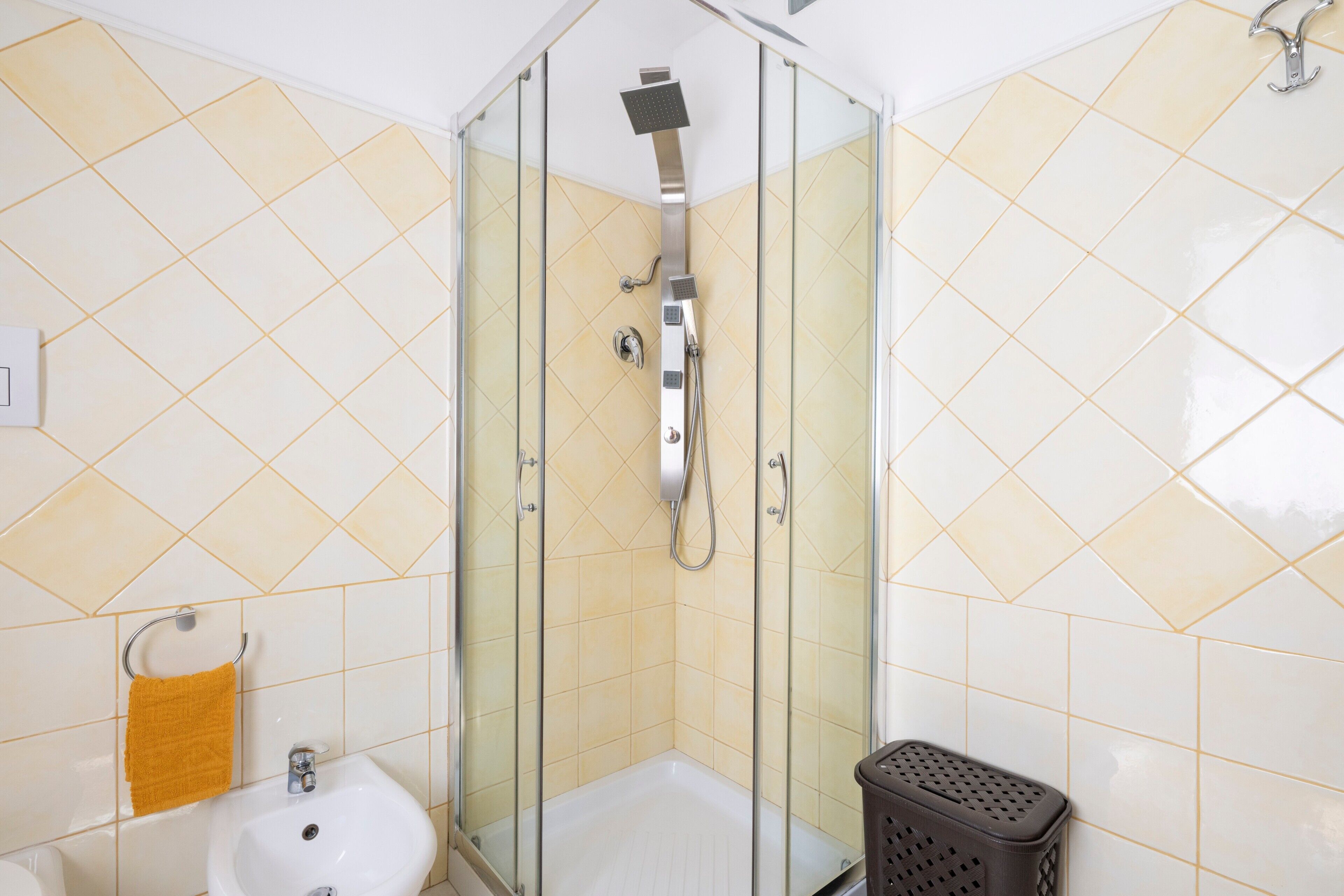 A glass-enclosed shower with a handheld showerhead and a wall-mounted faucet.