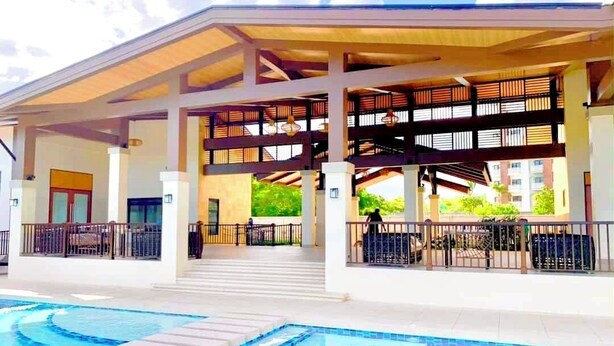 Un hotel con zona de piscina, asientos cubiertos y estructura de varios niveles.
