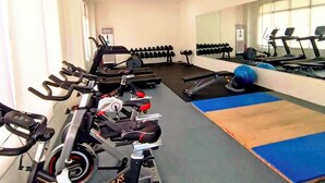 Un gimnasio con equipo de ejercicio, un espejo grande y una colchoneta azul.