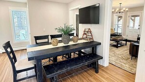 Un coin repas avec une table noire, des chaises et un téléviseur fixé au mur.