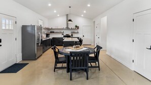 Una cocina moderna con comedor, paredes blancas y un refrigerador grande.