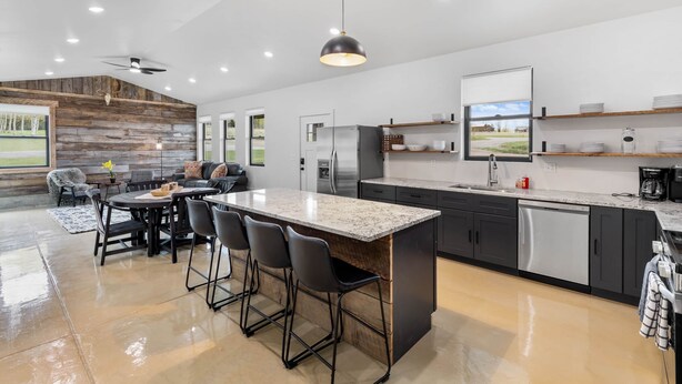 Una cocina moderna con una isla grande, electrodomésticos integrados y una zona de comedor con vistas.
