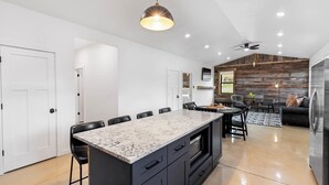 Una cocina moderna con una isla grande, armarios negros y una lámpara colgante.