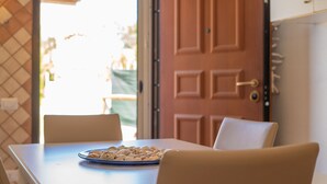 Une table à manger avec une assiette de noix, deux chaises, une porte en bois et une vue sur l’extérieur.