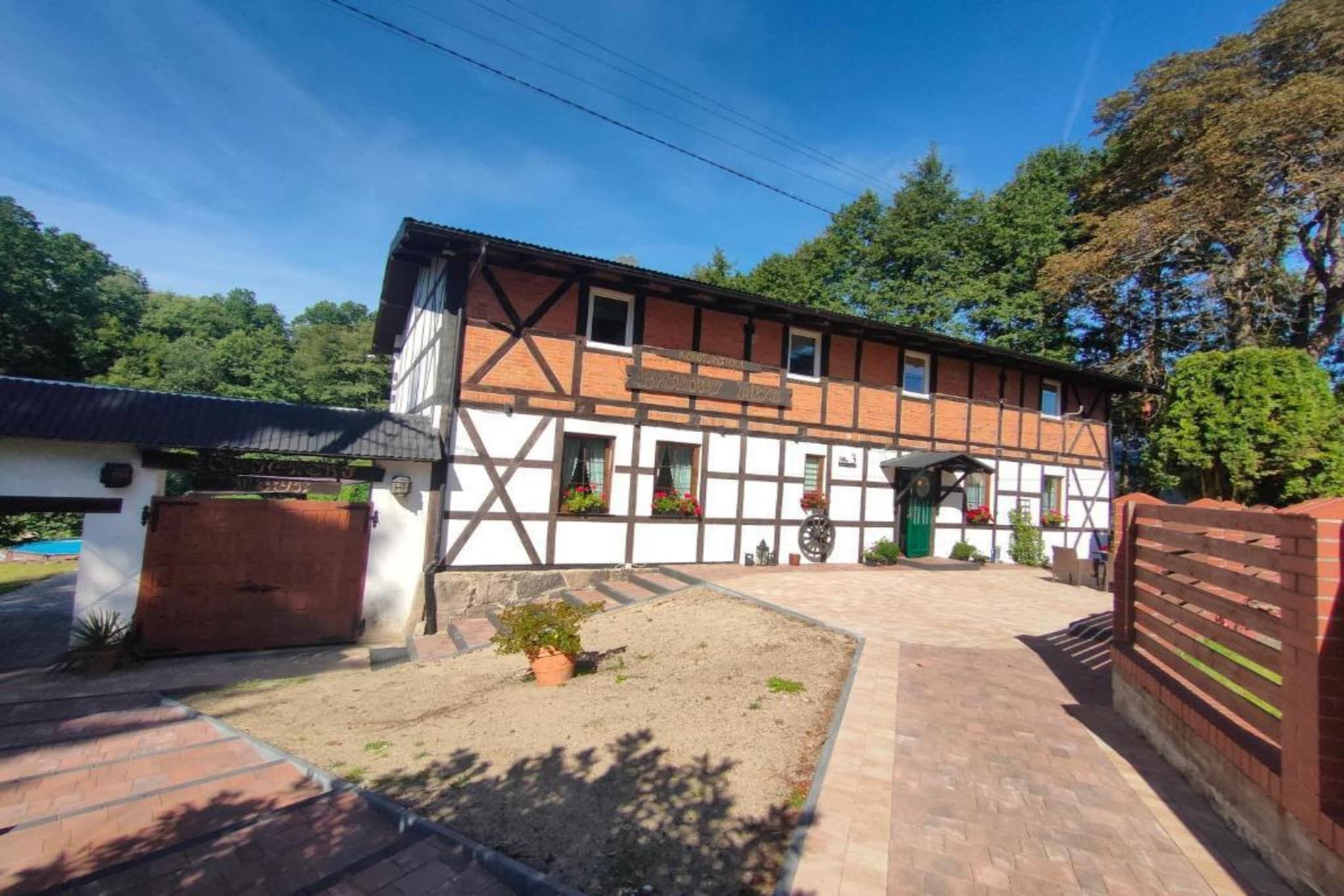 A traditional half-timbered building with a paved courtyard, a green door, and a small garden area.