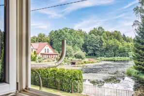 Ein Fluss mit einem Haus und Grünpflanzen im Hintergrund.