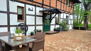 Ein Innenhof mit Tisch und Stühlen, einer grünen Tür und einem Gebäude mit Backstein und Fachwerkerbauweise.