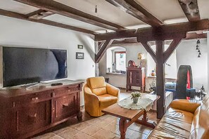 A living room with a television, leather armchair, sofa, wooden coffee table, and a fireplace. - Half of a holiday home, historic mill (Sianow)