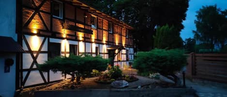 A traditional half-timbered building with a well-lit facade and a landscaped garden.