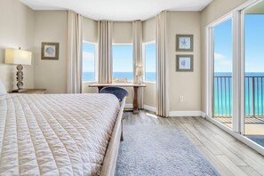 Ein Hotelzimmer mit einem großen Bett, einem Schreibtisch, einem Stuhl und Blick auf das Meer.