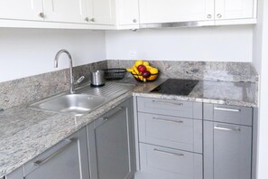 A kitchen with a stainless steel sink, granite countertop, and grey cabinets. - Elegant Coastal Base for 3 (Dziwnow)