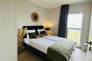 A double bed with a headboard, a bedside lamp, and a decorative mirror on the wall. - Elegant Coastal Base for 3 (Dziwnow)