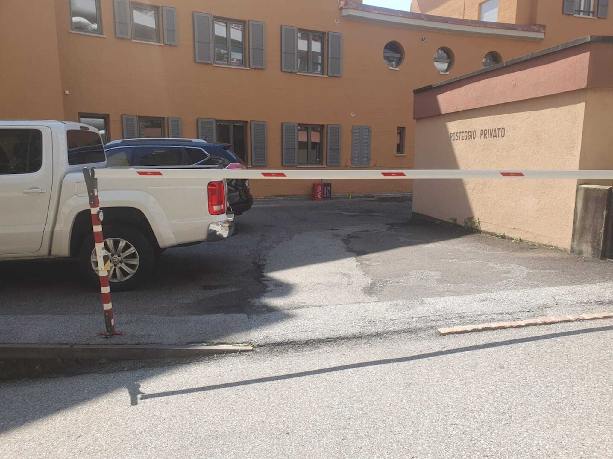 Ein verschlossenes Tor zu einem Gebäude, darin ein weißer Pritschenwagen geparkt.