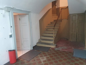 A staircase leading to an upper floor, a white door, a red trash can, and a patterned carpet. - Lake 0 Central Lugano Family Apartment Lake View (7 guests) (LUGANO)