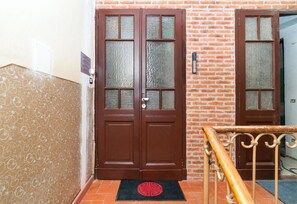 A double door with frosted glass panels, a metal handrail, and a doormat with a red circular design. - Lugano Deluxe 2 bedroom lake view (6 guests) (LUGANO)