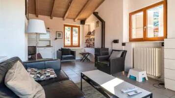 Una sala de estar con sofá, mesa de centro y chimenea. Cuenta con una zona de cocina con estufa y radiador.