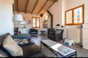 Ein Wohnzimmer mit einer Couch, einem Couchtisch und einem Kamin. Es gibt eine Küchenzeile mit einem Herd und einer Heizung.
