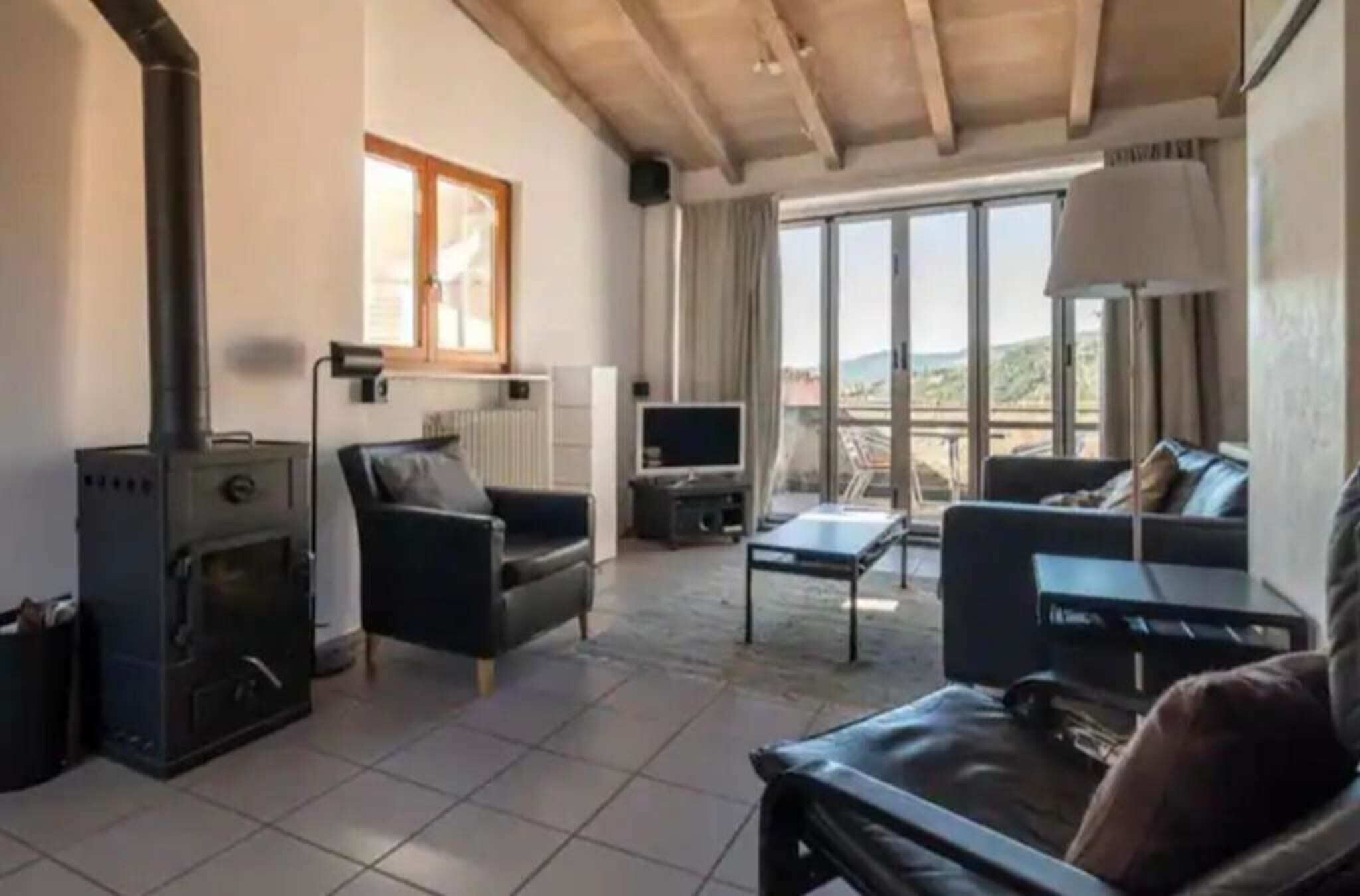 Ein Wohnzimmer mit Kamin, einer Couch, einem Fernseher und Blick ins Freie.