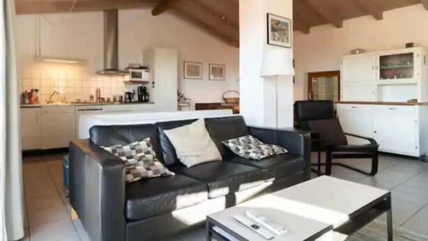 A living room with a black leather sofa, a white coffee table, and a black armchair. There is a kitchen in the background with white cabinets and a microwave. - Cadro Casa Vista (4guests) (SESTRI LEVANTE)