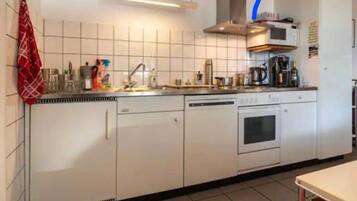 Una cocina con armarios blancos, microondas, estufa y lavabo.