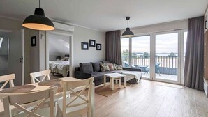 Ein geräumiger Wohnbereich mit einer Couch, Sesseln, einem Esstisch und einem Balkon mit Blick.