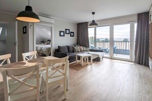 Ein geräumiger Wohnbereich mit einer Couch, Sesseln, einem Esstisch und einem Balkon mit Blick.