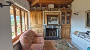 A cozy living room with a fireplace, wooden cabinets, and a sofa. - PREGASSONA Executive Apartment Lake View and Garden (8persons) (Lugano Pregassona)