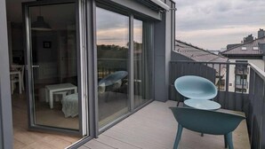 A balcony with a sliding glass door leading to a room, a small table, and a chair. - 6-Guest Beach Apartment in Dziwnów (Dziwnow)